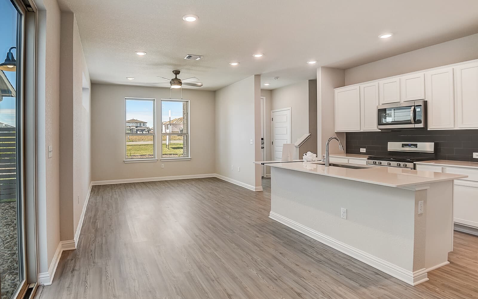 8209 Springsteen Drive Austin, TX 78744 - Photo 3 of 11 Kitchen with backsplash, white cabinetry, an island with sink, stainless steel appliances, and recessed lighting
