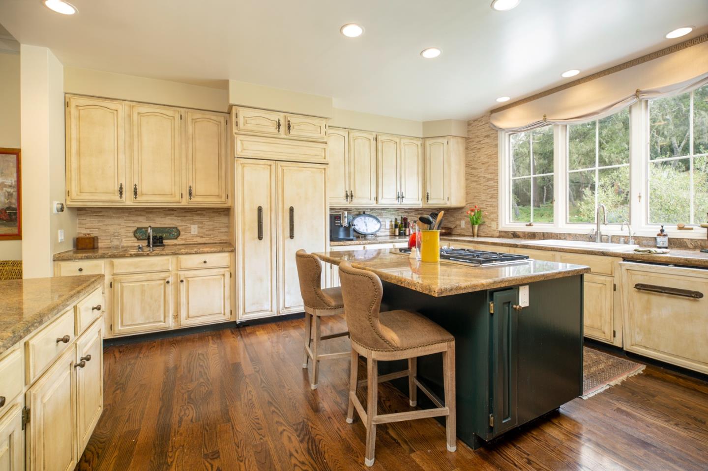 1534 Riata Road Pebble Beach, CA 93953 - Photo 7 of 50 a kitchen with a sink stove and white cabinets with wooden floor