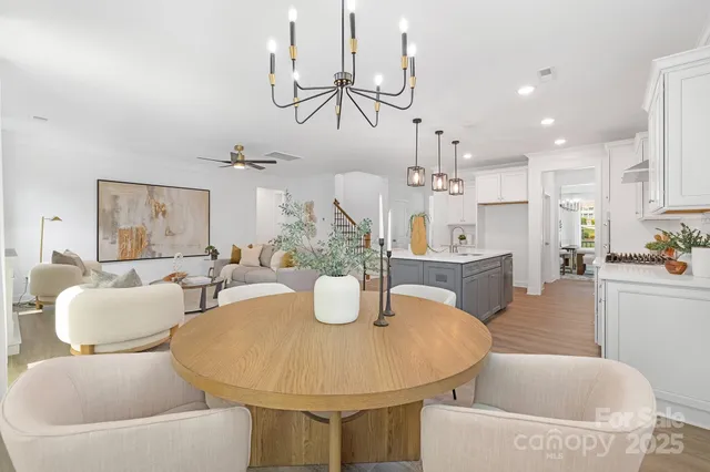 a dining room with kitchen island stainless steel appliances furniture a chandelier and kitchen view