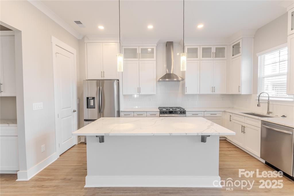 3110 Doe River Way, Unit RHODES Matthews, NC 28105 - Photo 42 of 48 a large white kitchen with kitchen island a sink dishwasher a refrigerator and white cabinets with wooden floor