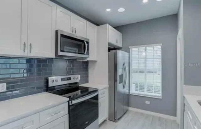 a kitchen with stainless steel appliances white cabinets and stove