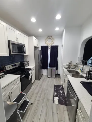 a kitchen with a refrigerator a sink and wooden floor