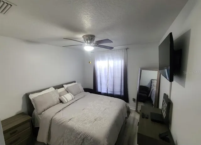 a bedroom with a bed and a flat tv screen on the dresser
