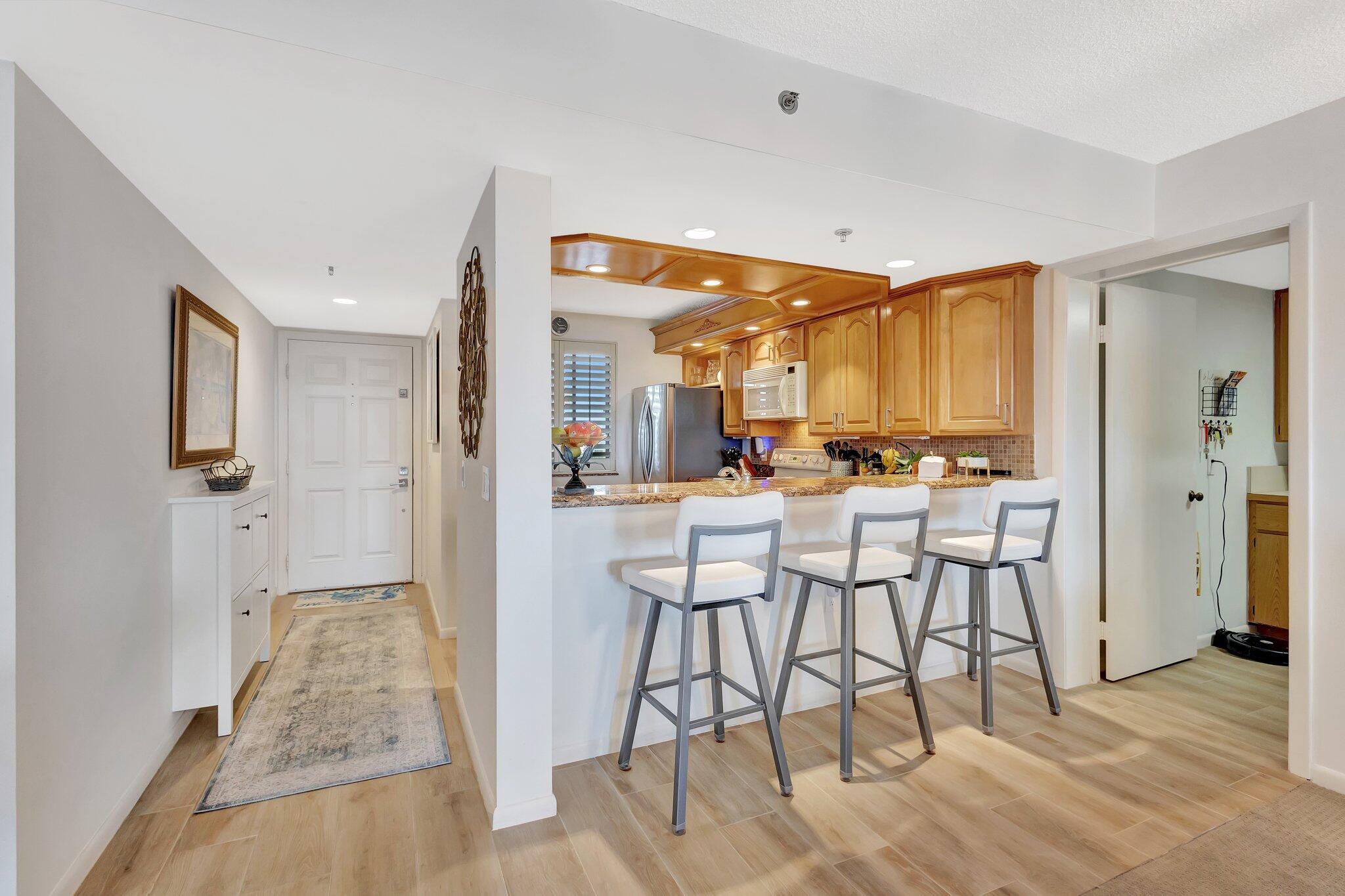 201 South Seas Drive, Unit 302 Jupiter, FL 33477 - Photo 9 of 19 a kitchen with stainless steel appliances kitchen island granite countertop a refrigerator and cabinets