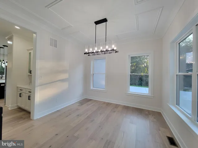 an empty room with wooden floor cabinet and windows