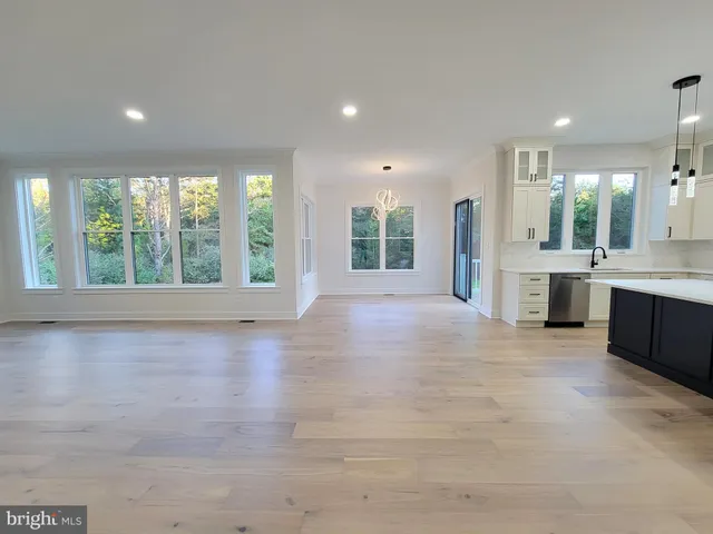 a large white kitchen with large windows and sink