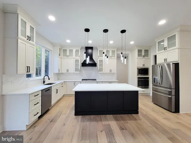 a large kitchen with stainless steel appliances a sink and cabinets