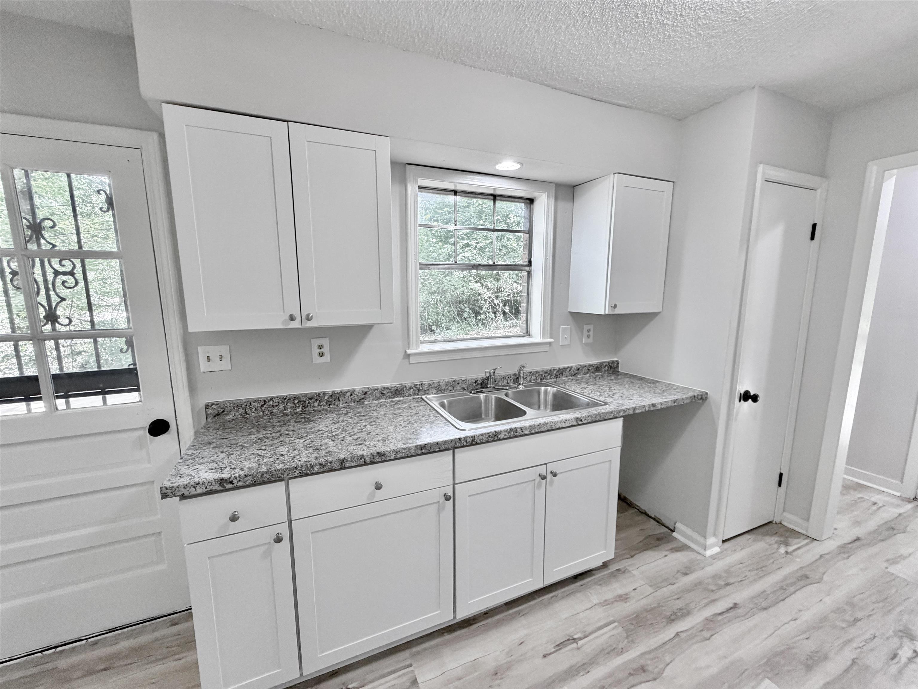 4278 Auburn Road Memphis, TN 38116 - Photo 9 of 28 Bright kitchen area featuring white shaker-style cabinetry, a double basin stainless steel sink, and speckled gray countertops