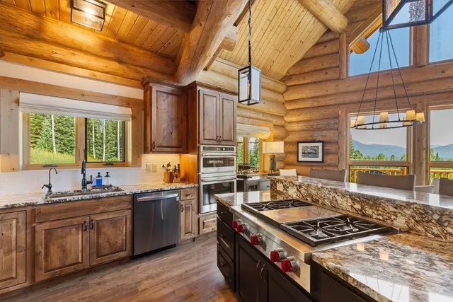 a kitchen with stainless steel appliances granite countertop a sink a stove and wooden cabinets
