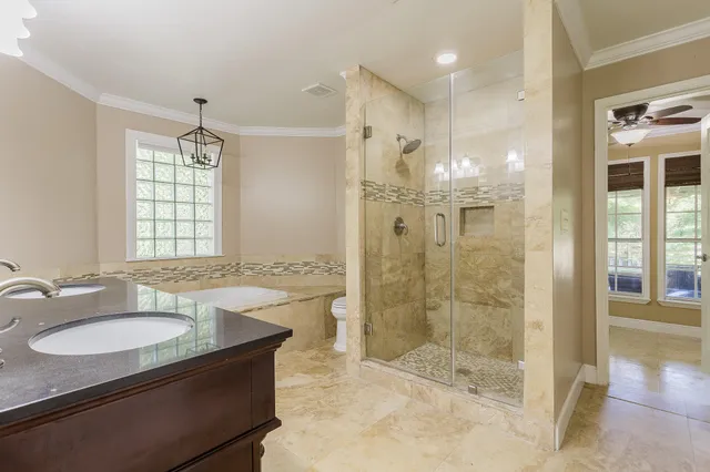 a spacious bathroom with a granite countertop double vanity sink a mirror and a bathtub
