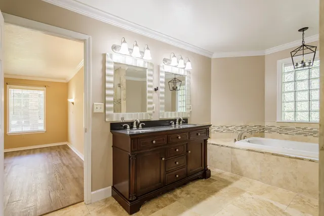 a spacious bathroom with a granite countertop double vanity sink a mirror and a bathtub