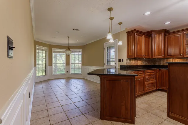 a kitchen with kitchen island granite countertop wooden cabinets a sink a window and stainless steel appliances