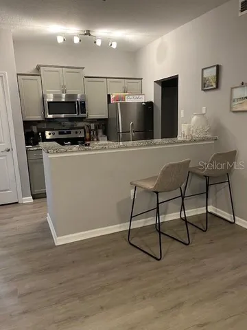 a kitchen with stainless steel appliances kitchen island granite countertop a sink and a refrigerator
