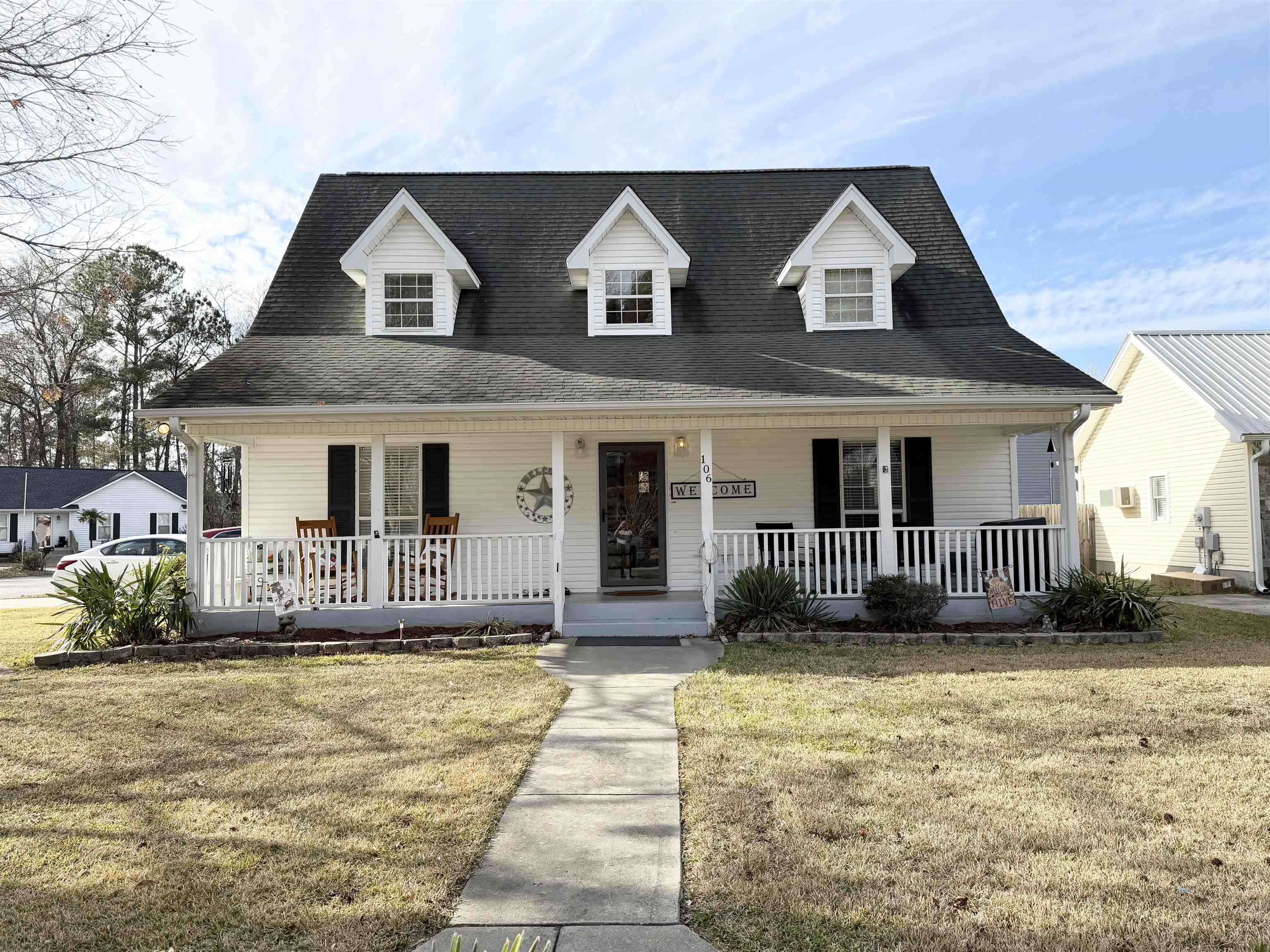 Cape cod-style house featuring a front yard, covered porch, and a shingled roof