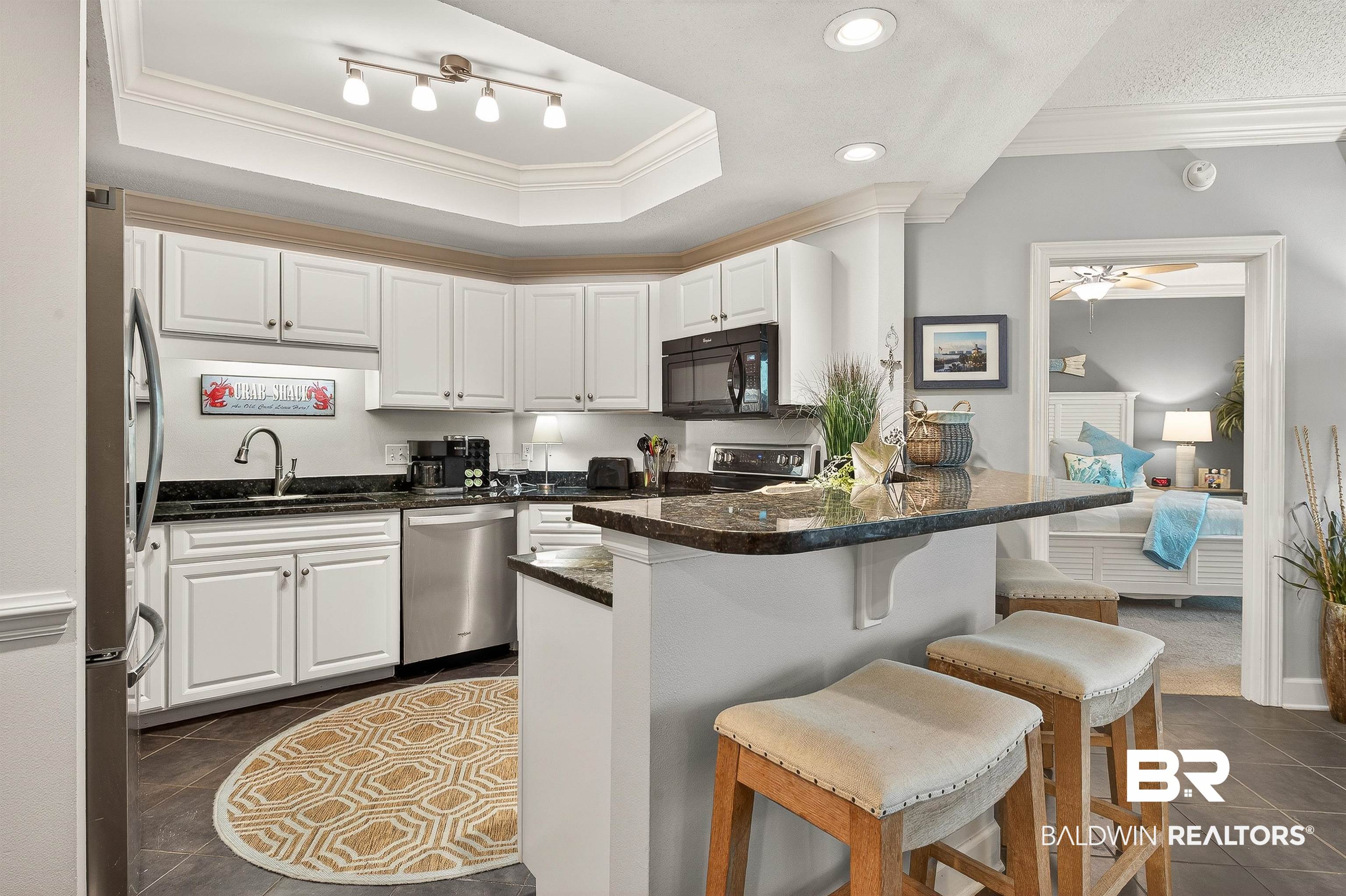 27582 Canal Road, Unit 2507 Orange Beach, AL 36561 - Photo 6 of 75 Kitchen featuring white cabinetry, ornamental molding, dark stone counters, a kitchen breakfast bar, and appliances with stainless steel finishes