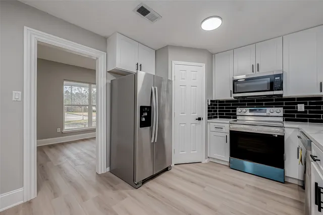 an empty room with wooden floor and windows