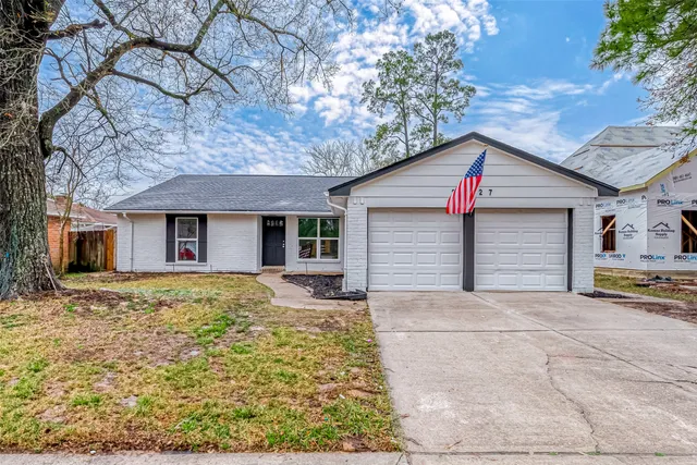 a view of a house with a yard and large tree
