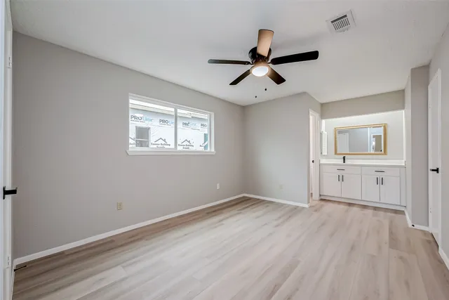 an empty room with wooden floor and ceiling fan