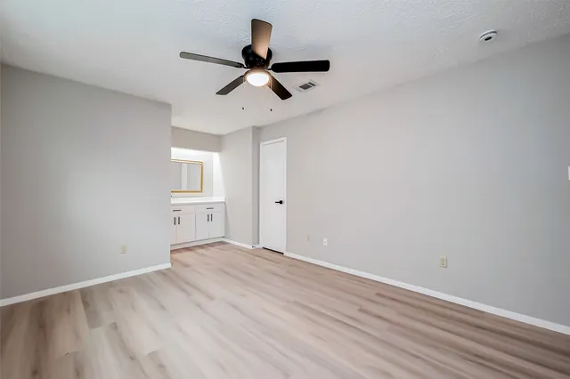 an empty room with wooden floor and a ceiling fan