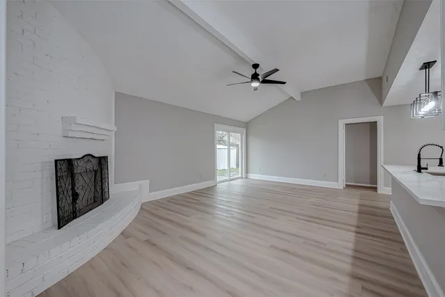 a view of a livingroom with a fireplace a ceiling fan and wooden floor