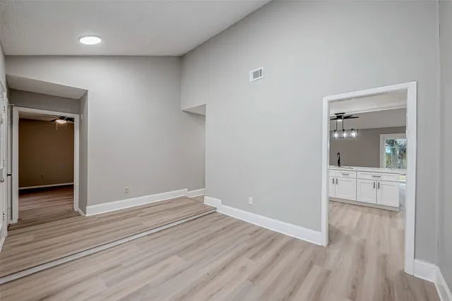 a view of empty room with wooden floor and fan