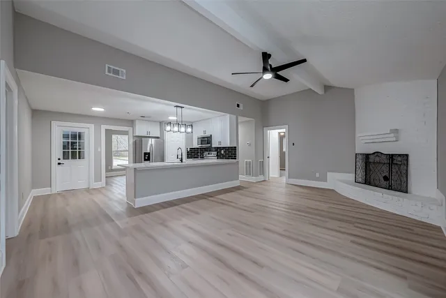 a kitchen with stove a microwave oven a sink dishwasher and white cabinets with wooden floor