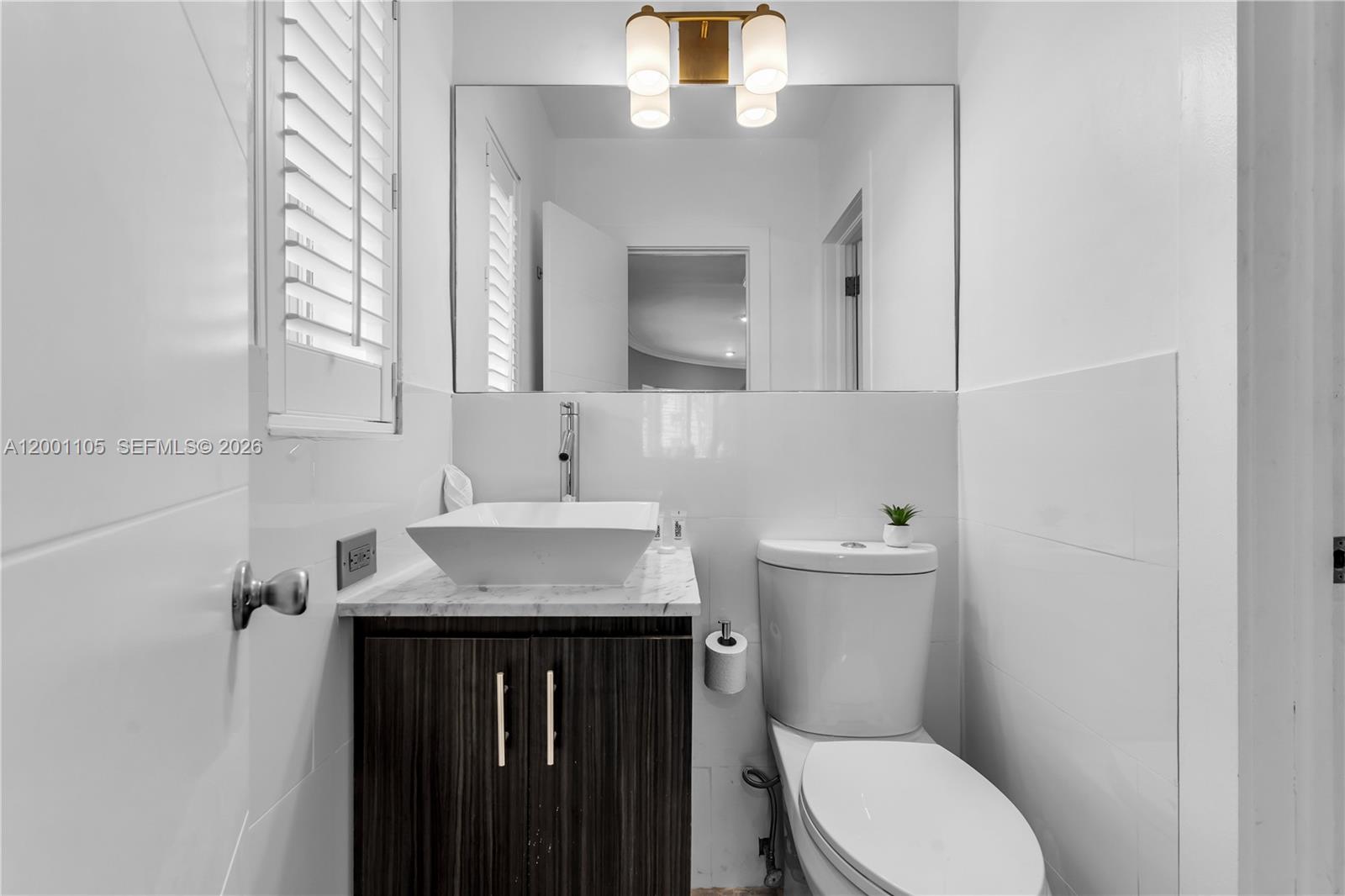 8101 Harding Avenue Miami Beach, FL 33141 - Photo 15 of 34 a bathroom with a sink vanity mirror and toilet