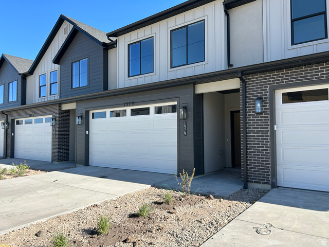 2011 West 1150 South, Unit 1042 Payson, UT 84651 - Photo 2 of 39 Photos are of model home.Contemporary townhome exterior featuring a white paneled garage door, dark brick accents, and vertical white siding
