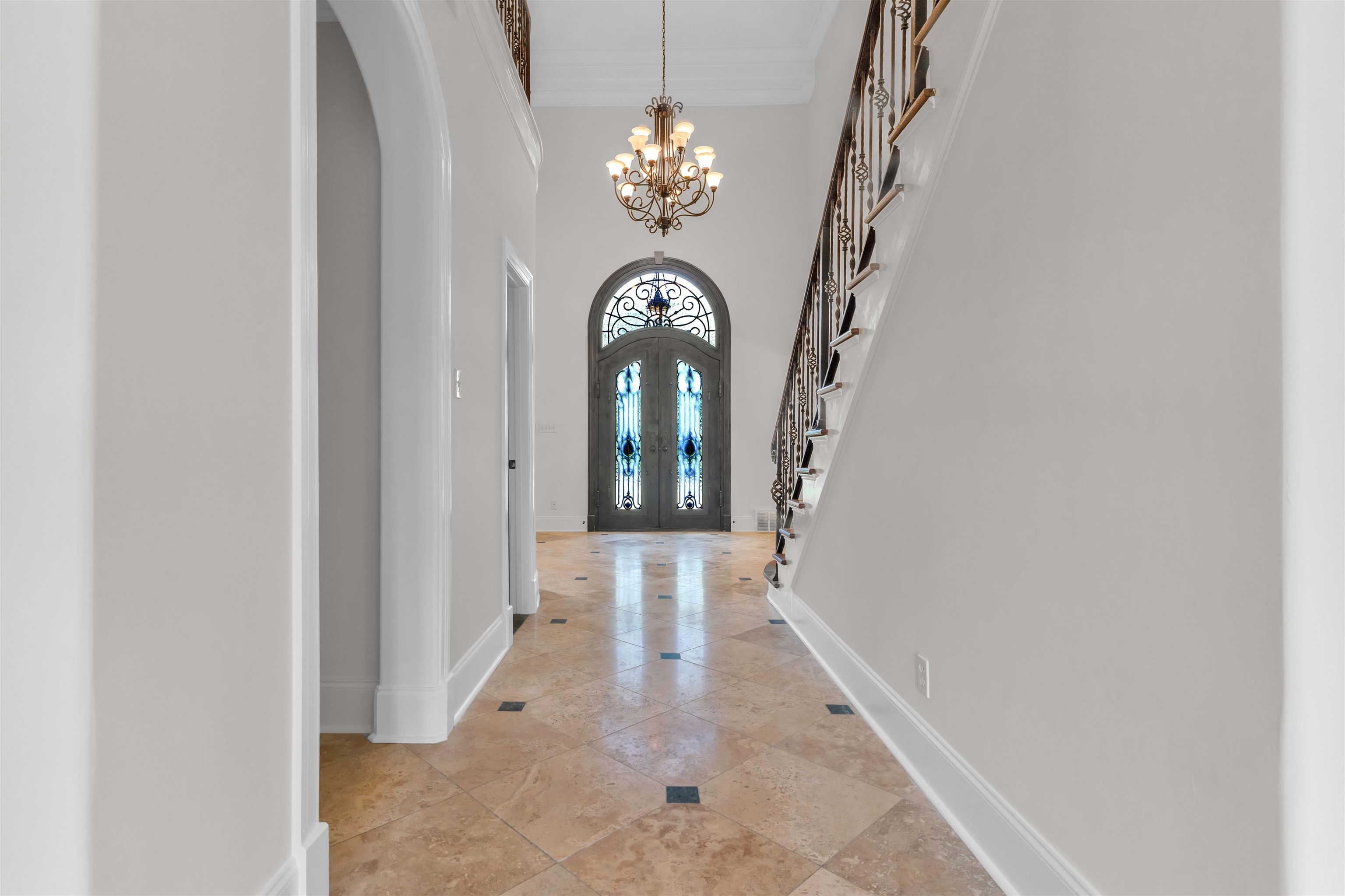 680 Highway 193 Collierville, TN 38017 - Photo 5 of 38 Grand entryway featuring a decorative double-door with arched transom, a wrought iron and wood staircase, a multi-tier chandelier, and light-toned tile flooring with dark accent squares