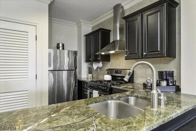 a kitchen with granite countertop a sink stainless steel appliances a refrigerator and cabinets