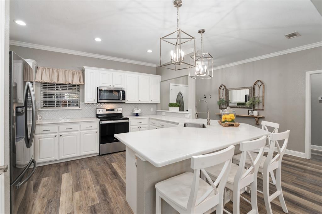127 Rueda Encina Street Gun Barrel City, TX 75156 - Photo 6 of 39 a open kitchen with stainless steel appliances granite countertop a sink dishwasher a stove a refrigerator with a dining table and chairs with wooden floor