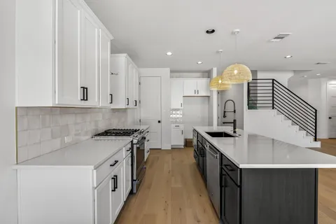 a kitchen with stainless steel appliances granite countertop white cabinets and a stove top oven