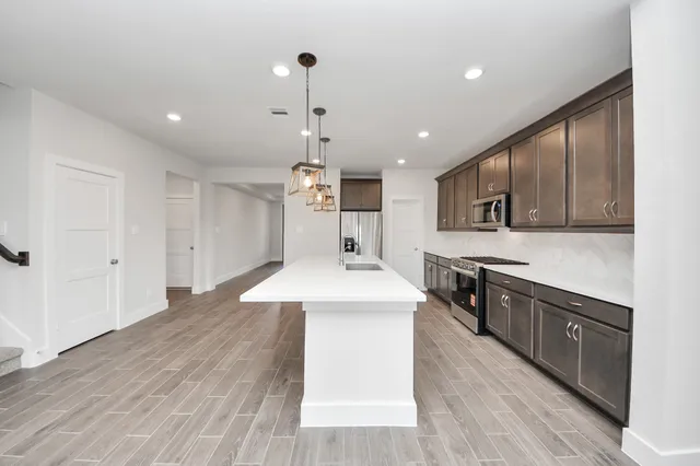 a large kitchen with stainless steel appliances granite countertop a sink a stove and a wooden floors