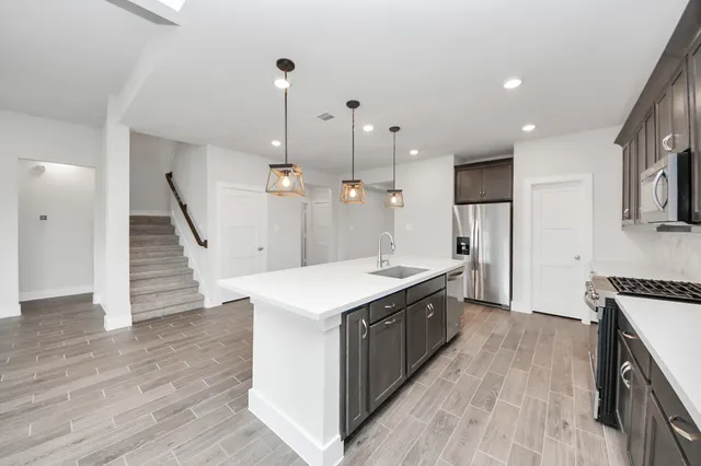 a large kitchen with stainless steel appliances granite countertop a large stove a sink dishwasher and a refrigerator with wooden floor