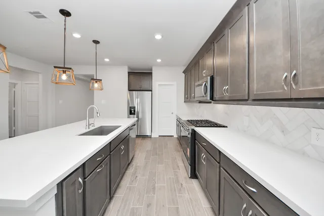 a kitchen with stainless steel appliances granite countertop a sink a stove and a wooden floors