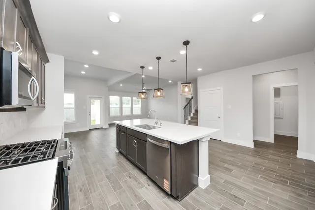 a large kitchen with stainless steel appliances a large counter top a stove a sink and a refrigerator