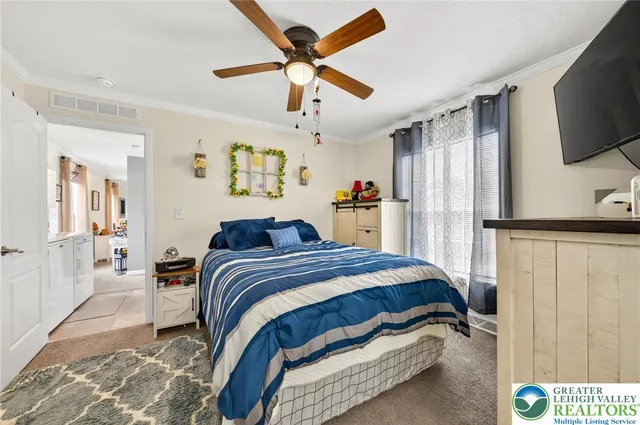 a bedroom with a bed and a flat tv screen on dresser
