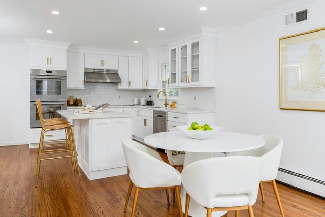 a kitchen with stainless steel appliances a dining table chairs and wooden floor