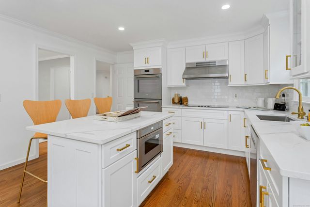 a kitchen with stainless steel appliances white cabinets and wooden floor