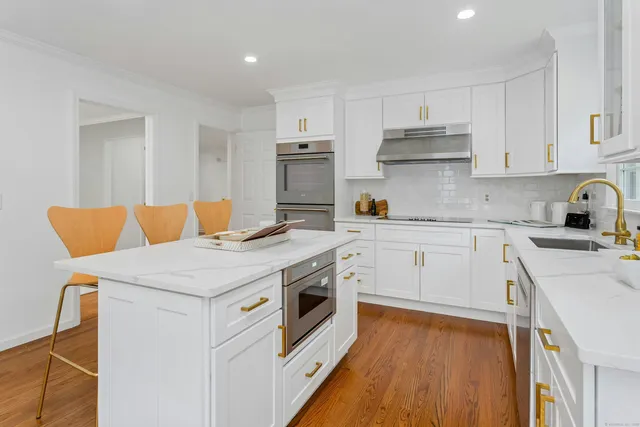 a kitchen with stainless steel appliances white cabinets and wooden floor