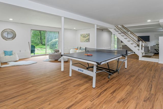 a room with wooden floor pool table and windows