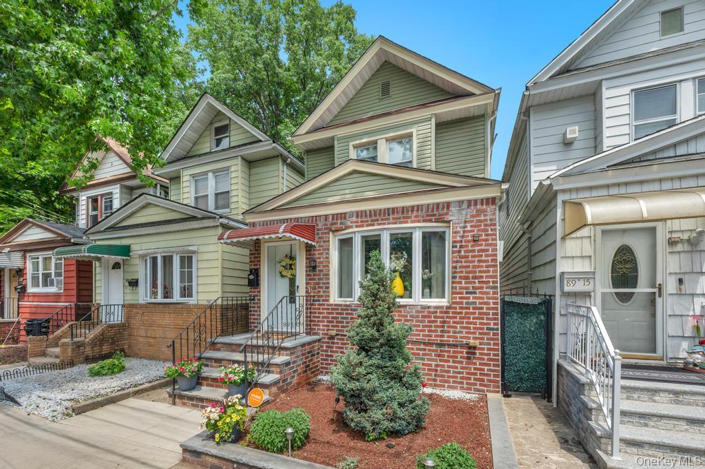 89-13 84th Street Queens, NY 11421 - Photo 3 of 34 Brick and siding exterior with a front bay window and a sloped front yard featuring landscaping and a paved walkway