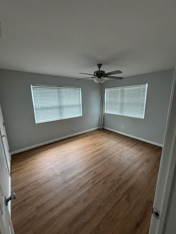an empty room with wooden floor cabinet and windows