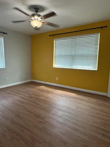 a view of empty room with wooden floor and fan