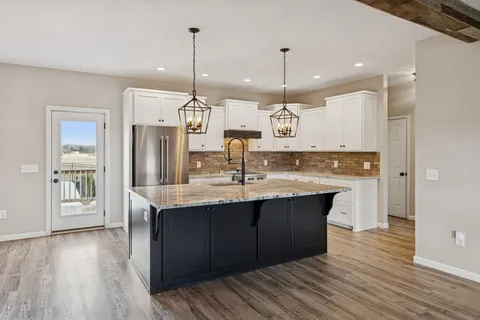 a kitchen with granite countertop a sink a stove and refrigerator