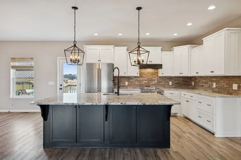 a kitchen with stainless steel appliances granite countertop a stove a refrigerator and a sink