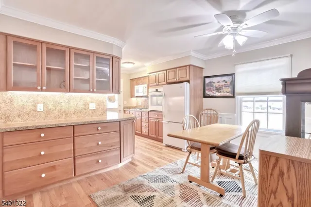 a kitchen with a stove a refrigerator a sink a dining table and chairs with wooden floor