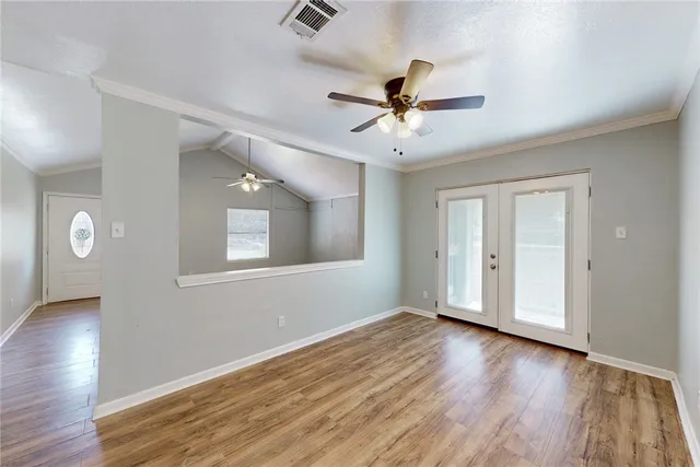 a view of an empty room with wooden floor and a window