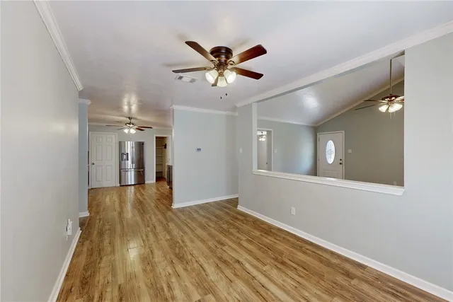 a view of an empty room with window and wooden floor