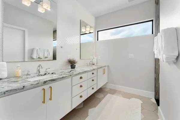 a bathroom with a granite countertop double vanity sink mirror and bathtub